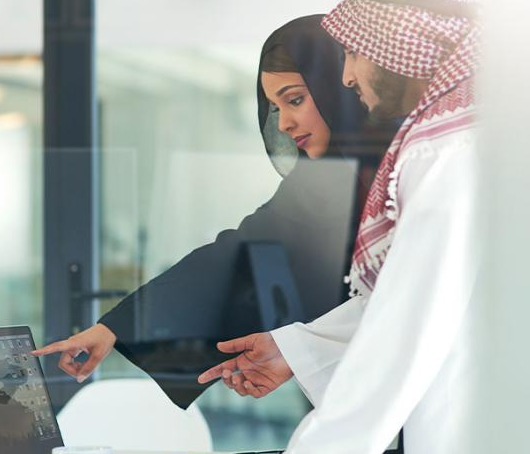 Two colleagues reviewing work on a laptop